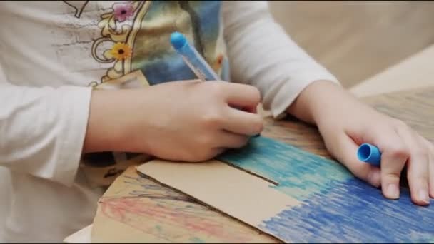 Ragazza dipinge figura di cartone con pennarello blu a tavola — Video Stock