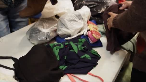 Доброволец проверяет блузки сортировки одежды на складе с стойкой — стоковое видео