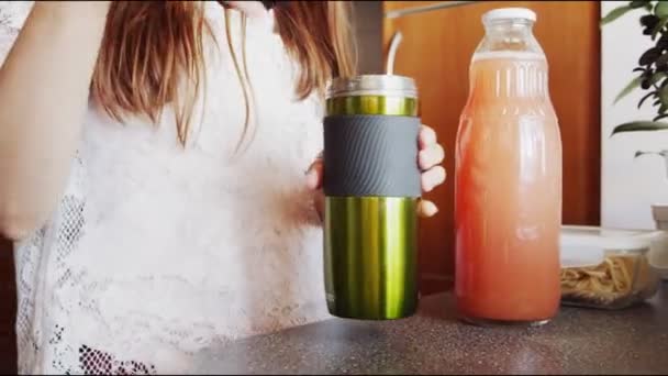 Chica vierte jugo de manzana en el termo en la mesa en la cocina — Vídeos de Stock