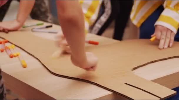Děti malují lepenkovou žirafu se značkami na stole — Stock video