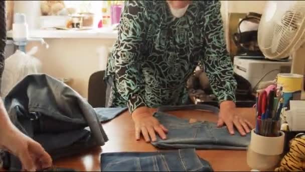Alfaiates do sexo feminino trabalhar com peças de jeans velhos em grande mesa — Vídeo de Stock