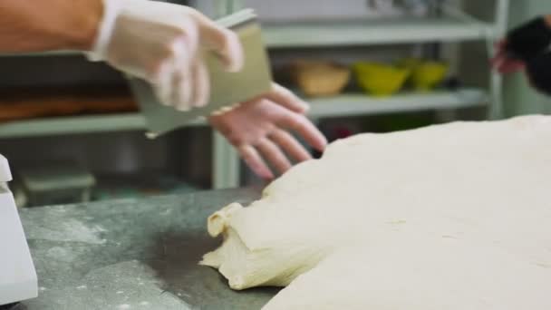 Bakker snijdt stuk deeg met mes op tafel in de bakkerij — Stockvideo