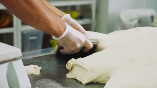 Chef-kok in handschoenen snijdt stuk deeg met mes in bakkerij — Stockvideo