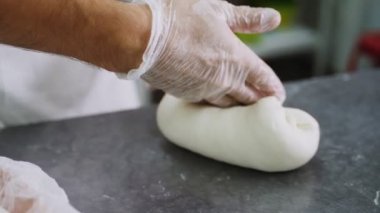 İşçi ekmek hamuru yapıyor. Ağır çekimde temiz masa üzerinde.