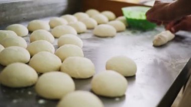 Fırıncı, metal masada lezzetli hamurdan turta yapıyor.