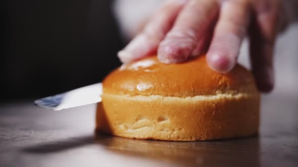 Woman cuts fresh bun to make hamburger on table closeup — Stock Video