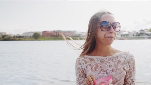 戴眼镜的女人在蓝河边休息时吃苹果片 — 图库视频影像