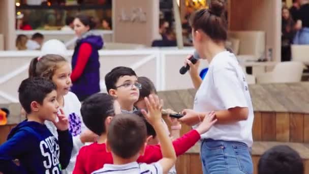 Ragazza volontaria fa domande ai bambini nel centro commerciale — Video Stock