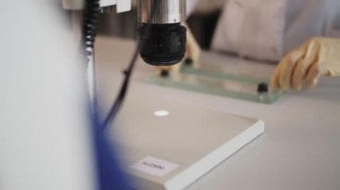 Kadın, numuneyle mikroskoba slaytı yakın çekim masasına koyar.