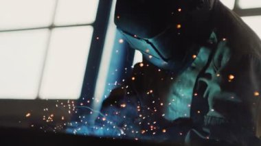 Koruyucu maskeli kaynakçı atölyede detaylarla çalışır