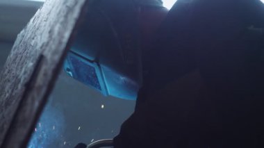 İşçi, atölyedeki inşaat sahasında metal parçaları kaynaklıyor