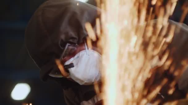 Man met masker snijdt metalen deel achter vonken regen in de winkel — Stockvideo