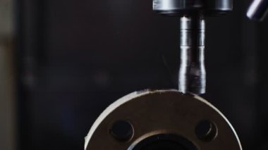 Sondaj makinesi siyah duvarda metal flanşlarda delik açıyor.