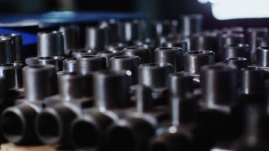 Masanın üzerinde koyu arkaplanda sayısız parlak metal boru eklemleri var.