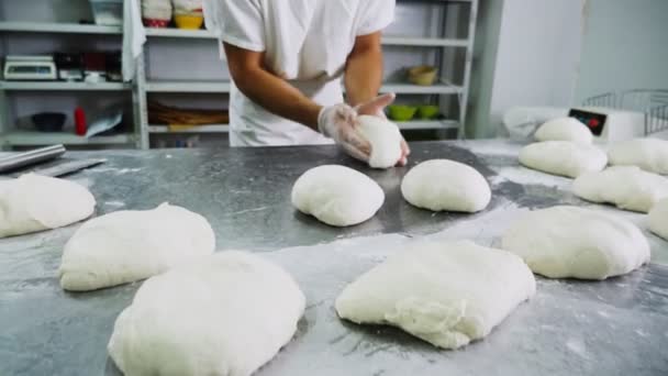 Шеф-повар разминает дрожжевое тесто на металлическом столе в пекарне — стоковое видео