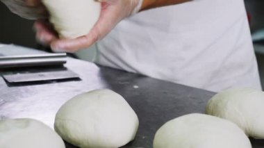 Eldivenli genç adam taze hamur parçalarıyla ağır çekimde çalışır.