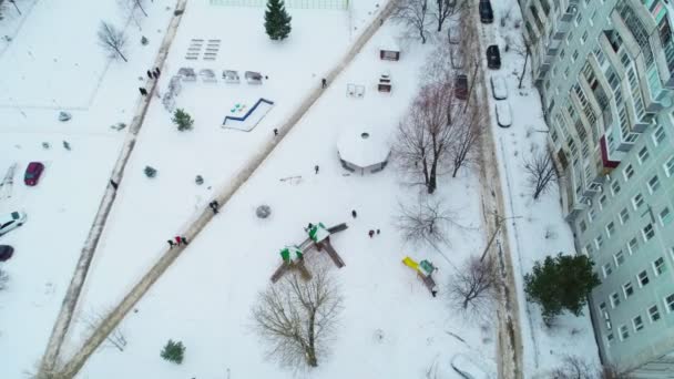 Люди ходять по засніженому двору серед житлових будівель — стокове відео