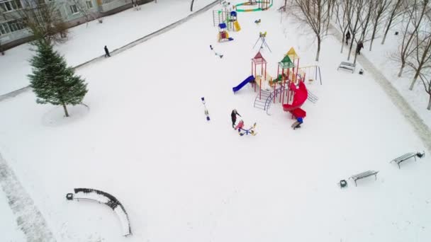 Anne küçük çocukla kış günü oyun bahçesinde oynuyor. — Stok video