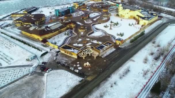 Zimní zábavní park s atrakcemi na zamrzlém břehu řeky — Stock video