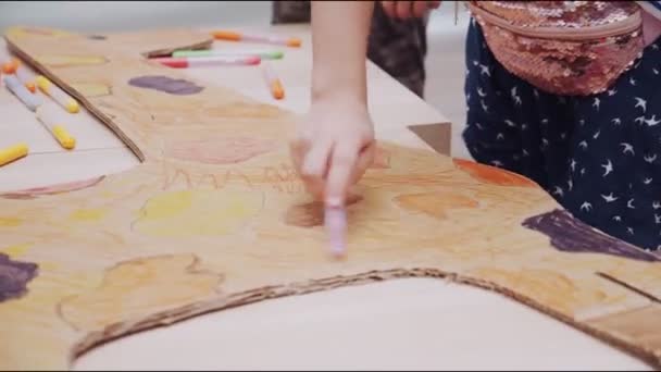 Girl paints cardboard giraffe on table in playroom closeup — Stock Video