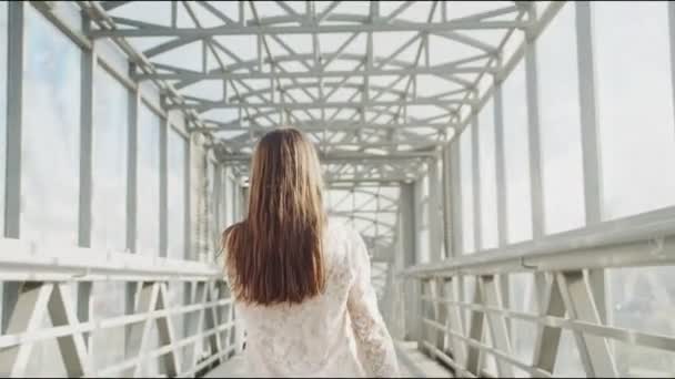 Vrouw in wit lacy blouse loopt langs voetgangersbrug — Stockvideo