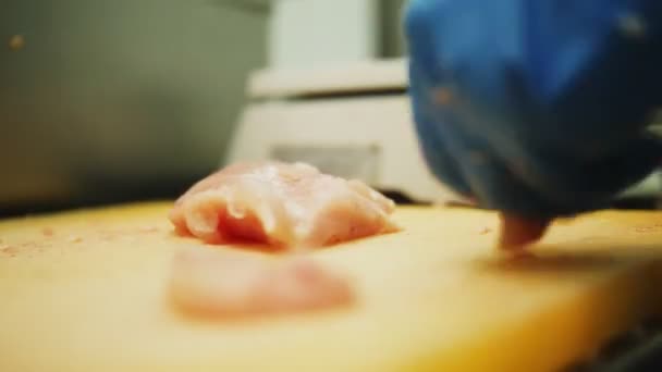 Werknemer snijdt kipfilet met scherp mes op tafel closeup — Stockvideo