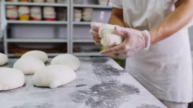 Fırıncı, atölyedeki metal masada hamurla çalışıyor.