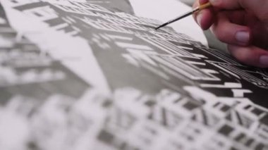 man draws building with brush and black color in office