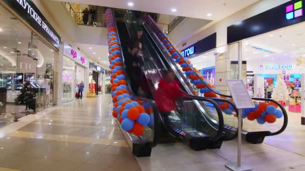 Клиенты ездят на эскалаторе, украшенном яркими воздушными шарами — стоковое видео