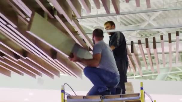 Строители устанавливают доски на декоративные элементы под потолком — стоковое видео
