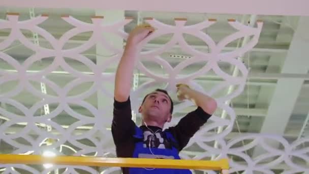 Arbeiter mit Kopfhörern dekoriert Decke in Einkaufszentrum — Stockvideo
