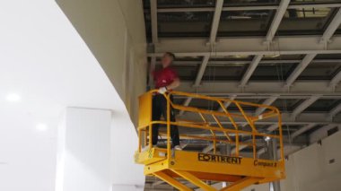 İşçi sarı makasla duvarı beyaz renge boyuyor.