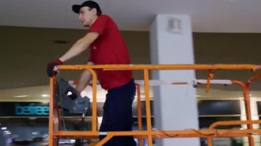 İnşaattaki platformdaki tişörtlü işçiye hareket