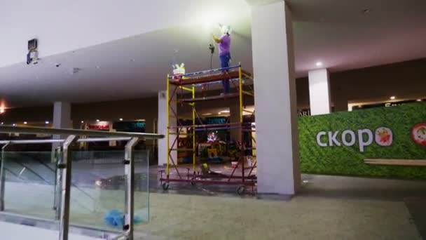 Byggare med lampa polerar vitt tak på marken i hallen — Stockvideo