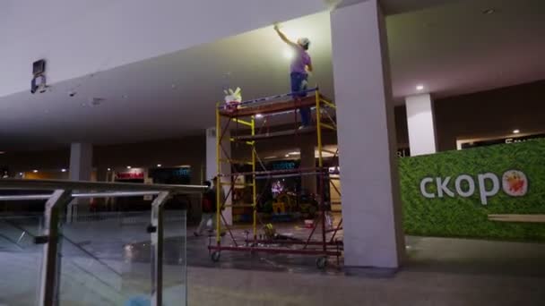 Женщина с лампой делает отделочные работы на потолке в зале — стоковое видео
