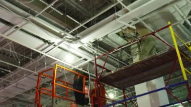 Kaynakçı, alışveriş merkezinin tavanına metal parçaları bağlıyor