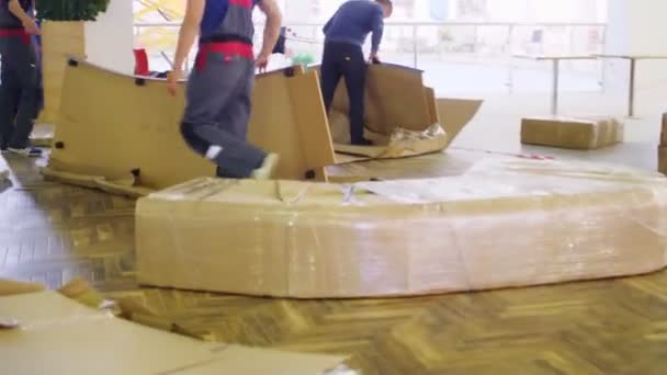 Trabajadores desempaquetan detalles envueltos con papel de aluminio en el centro comercial — Vídeos de Stock