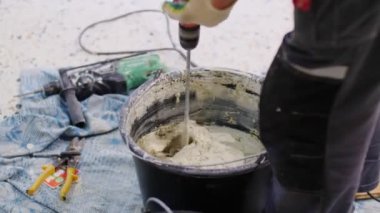 employee prepares wet mix in bucket at construction closeup