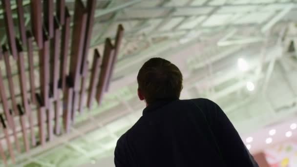 Работник смотрит на деревянные украшения на потолке торгового центра — стоковое видео