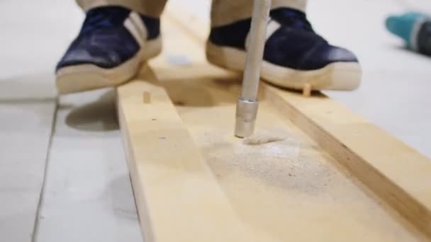Laborer makes hole in wooden detail on floor closeup — Stock Video