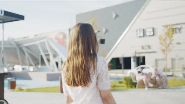 Vrouw in blouse wandelingen naar winkelcentrum langs zonnige plein — Stockvideo