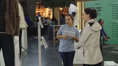 Gönüllü kız dijital bilgi standının yanında misafir ile konuşuyor