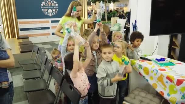 Kleine Kinder mit Frau zeigen neue Plastikflaschen im Forum