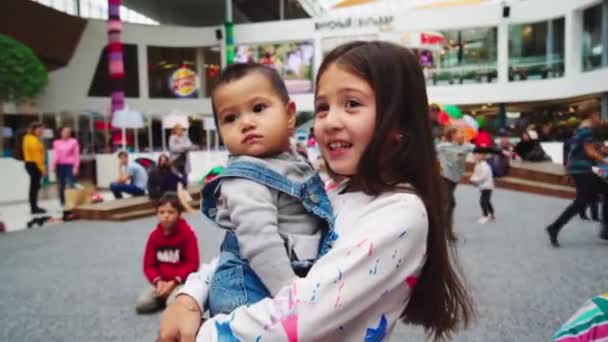 Kız, küçük kardeşini alışveriş merkezinde oyalıyor. — Stok video
