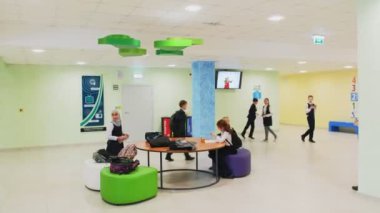 Neşeli öğrenciler aydınlık salondaki yuvarlak masanın yanında dinleniyorlar.