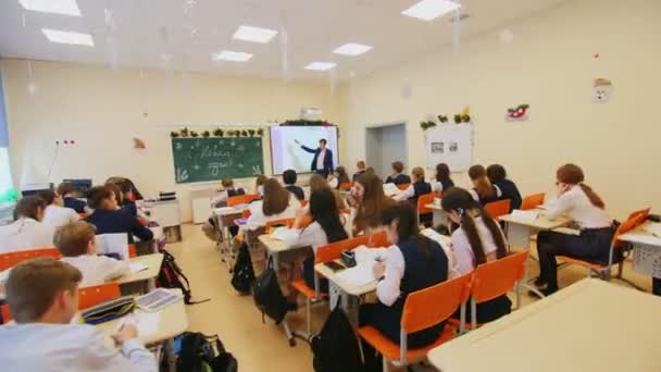 Students listen to teacher explaining lesson in classroom — Stock video