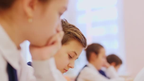 Schoolboy writes listening to teacher at desk in classroom — Stock video