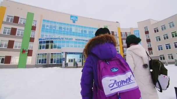 Meisjes in jassen lopen naar school op koude winterdag achterkant — Stockvideo