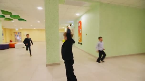 Små skolebørn lege tag kører langs rummelig hal – Stock-video