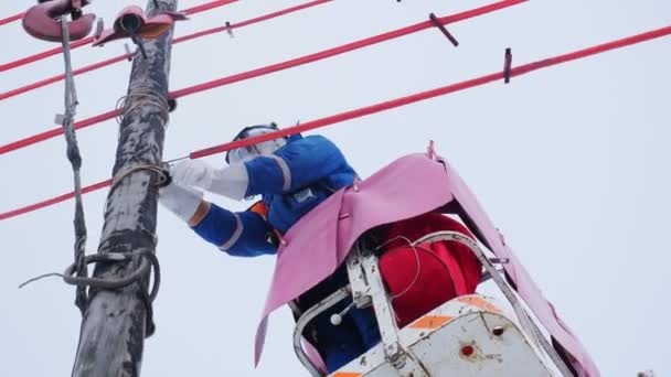 Empleado fija la línea de transmisión de energía en el viejo poste de madera — Vídeos de Stock